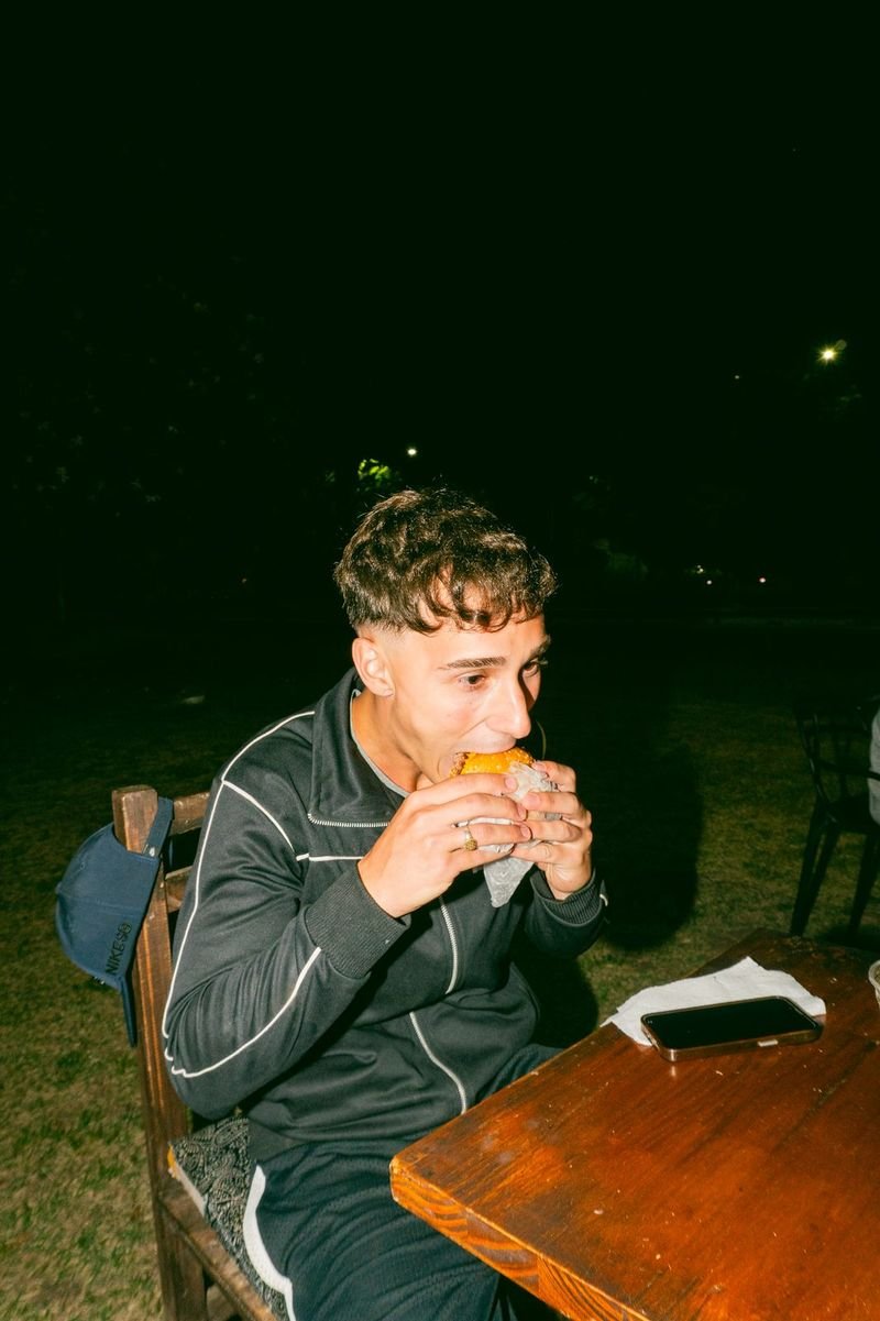 Invitado comiendo una hamburguesa Epifanía sentado a una mesa de madera