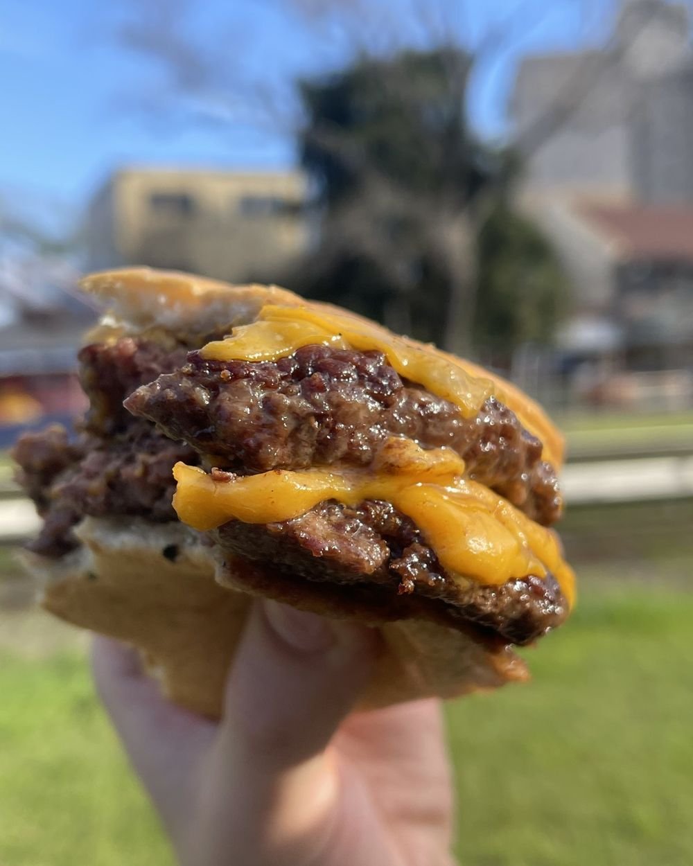 Hamburguesa doble con cheddar fundido, mordida, con la carne jugosa a la vista